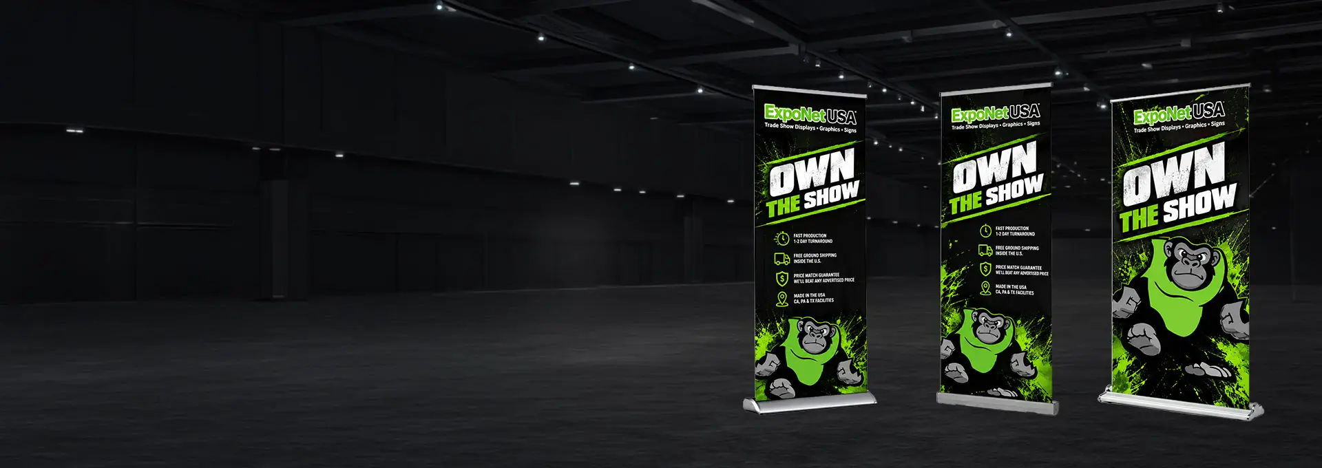 Three ExpoNet USA Own The Show retractable banner stands with the gorilla mascot, standing in an empty exhibition hall